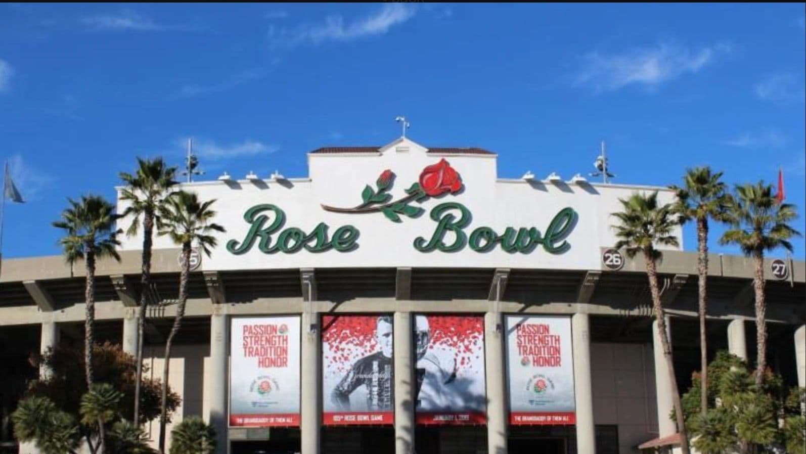 Entrance of the Rose Bowl stadium with palm trees and clear blue sky.